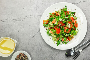 Lazy mediterranean salad with tomatoes, cucumber, coriander, onions, olive oil and lemon in a white ceramic plate selective focus. Healthy vegetarian food, oriental and Mediterranean cuisine. Top view