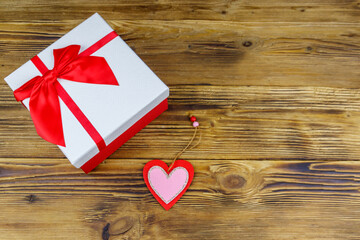 Gift box and red heart on a wooden background. Valentine's Day concept