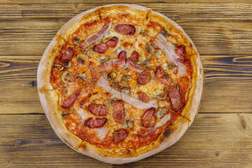 Delicious fresh pizza with sausage, mushrooms and cheese on a wooden table. Top view