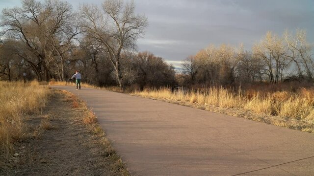 Recreational senior male inline skater in skating on a paved bike trail along Poudre River in Fort Collins, Colorado, fall or winter sunset scenery