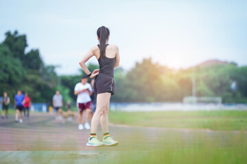 Obraz premium A mature beautiful Asian woman in sports outfits stretching before workout outdoor in the city stadium park in the morning to get a healthy lifestyle. Healthy young woman warming up outdoors