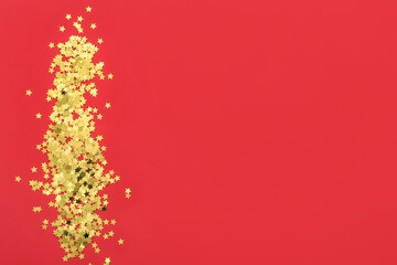 Heap of golden confetti on red background