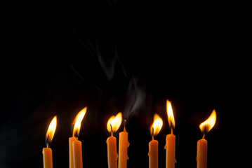 Group of candles, front view with light of beautiful bright yellow golden flames on black background. Ideas for Halloween, Christmas, Home, Romance, Love, Copy space for you
