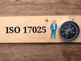 Miniature people,compass and wooden written with text ISO 17025 on wooden background.