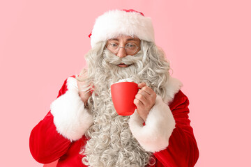 Santa Claus with cup of hot cocoa and bag on red background