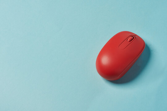 Red wireless mouse on blue background. Computer mouse.