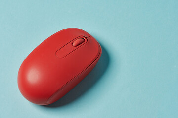 Red wireless mouse on blue background. Computer mouse.