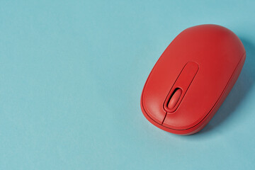 Red wireless mouse on blue background. Computer mouse.