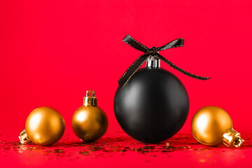 Black and golden Christmas balls on red background