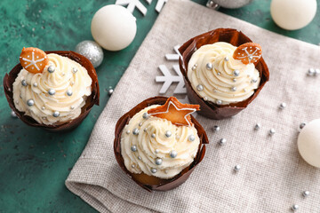 Delicious cupcakes and Christmas balls on green background