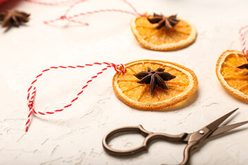Christmas decorations made of dried orange slices and scissors on light background, closeup