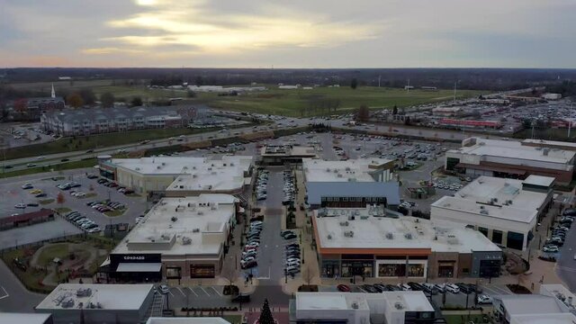 Dark aerial dolly shot of condominiums and a shopping center in Lexington Kentucky with a sunset in the background. 4k