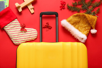 Composition with suitcase, Santa hat, sock and wooden airplane on color background, closeup. Christmas vacation concept