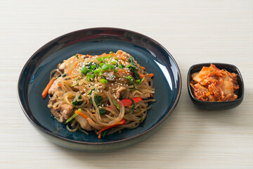 japchae or stir-fried Korean vermicelli noodles with vegetables and pork topped with white sesame