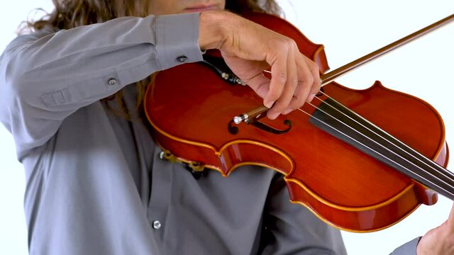 Latino violinist with long hair and goatee performing song on red violin against white backdrop
