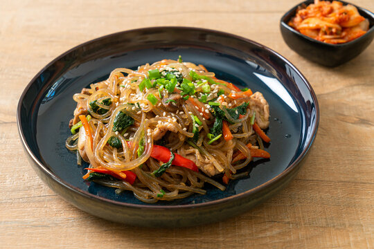 japchae or stir-fried Korean vermicelli noodles with vegetables and pork topped with white sesame