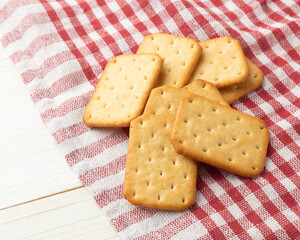 Cracker cookies with tablecloth on white wooden table background.