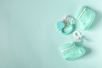 Flatley on the subject of things for a child. Children's knitted shoes, a bright toy and a baby pacifier on a blue background of the copy space