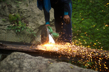 Professional Asian male artisans are cutting metal with a rotating diamond blade. To build an...