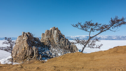 A picturesque two-headed rock, devoid of vegetation, against the background of a frozen lake and...