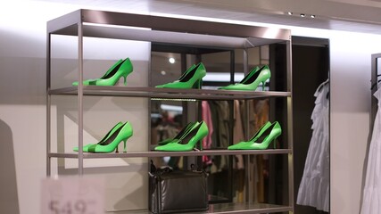 Elegant stylish trendy lime green high heels shoes in a row on the metallic showcase in luxury fashion retail store in the shopping mall