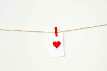 Valentine's Day card with red heart hanging on a rope on clothespin. February 14. Love background