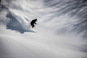Naklejka na ściany i meble Skier riding perfect powder snow dressed in black shot from high above.