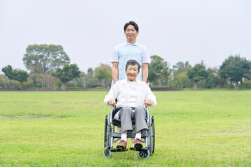 Fototapeta premium 介護士と車椅子に乗る高齢者 屋外