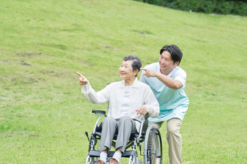Fototapeta premium 介護士と車椅子に乗る高齢者 屋外