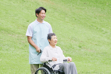 介護士と車椅子に乗る高齢者　屋外