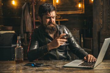 Bearded man is drinking expensive whisky. Old traditional whiskey drink. Man with beard holds glass brandy.