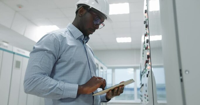 Portrait of an engineer in a hard hat holding a tablet.