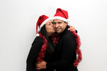Latino man woman couple with Christmas hat and garland as scarf show their love and excitement for the arrival of December and celebrate Christmas as a family
