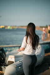 Sporty woman on the seashore wearing white shirt and leggings. Clothed fitness woman on the beach.