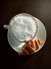 a cup of coffee and croissant in the black background