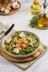 Arugula salad with shrimp and champignons, olive oil and dill on a wooden board on a white surface