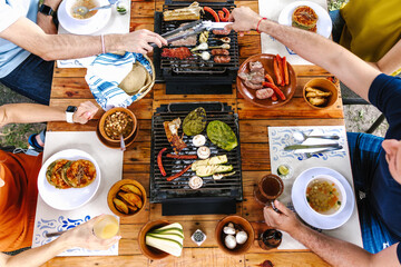 Group of friend eating mexican tacos and traditional food, snacks and people's hands over table, top view. Mexican cuisine