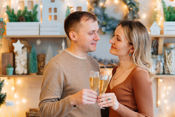 a couple in love with glasses of champagne in the christmas's kitchen. romantic.