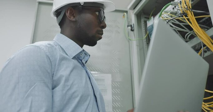 man using a laptop while working in a server room