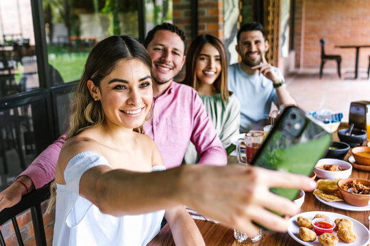 Group of latin friends taking a photo selfie and eating mexican food in the restaurant terrace in Mexico Latin America