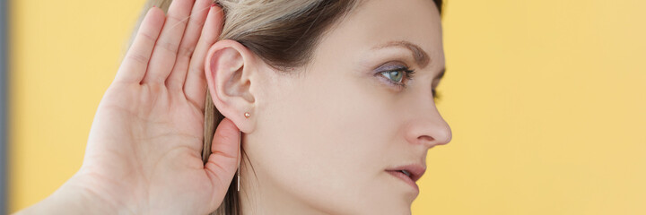 Deaf-mute woman holding her hand near ear