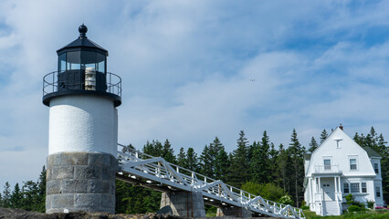 Beautiful white house and Marshall Point Lighthouse with the background of pine trees, Camden, USA