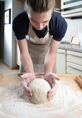 Young man and child knead dough for baking scones
on the background of a home kitchen.