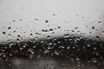 Contrast rain drops on transparent window glass at rainy autumn day on blurred dark light gradient backdrop - sadness mood background texture