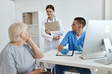 Obraz premium female patient sitting in hospital office with doctor and nurse communicating