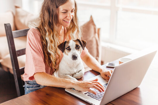 Female Working On Laptop With Cute Dog