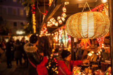 Lampe mit Bastgeflecht an weihnachtlichem Marktstand vor unscharfem Hintergrund