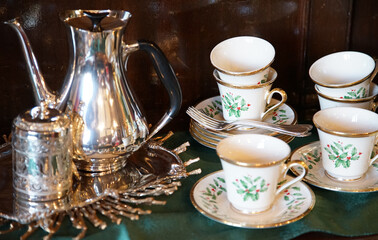 Silver pot and ceramic cup for tea on the table