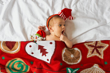 Little newborn baby, wearing Santa hat under blanket