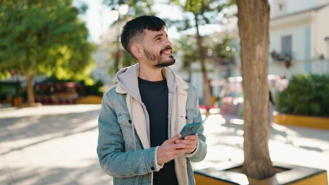 Young hispanic man smiling confident making photo by the smartphone at park